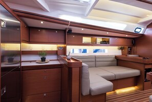 A compact, modern interior with wooden cabinetry, a cushioned seating area, and a small kitchenette. - Sun-Kissed Sailing Adventure in Sibenik, Croatia (Primošten)