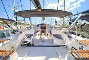A sailboat's deck with a steering wheel, helm station, and a small cabin. - Sun-Kissed Sailing Adventure in Northern Croatia (Punat)