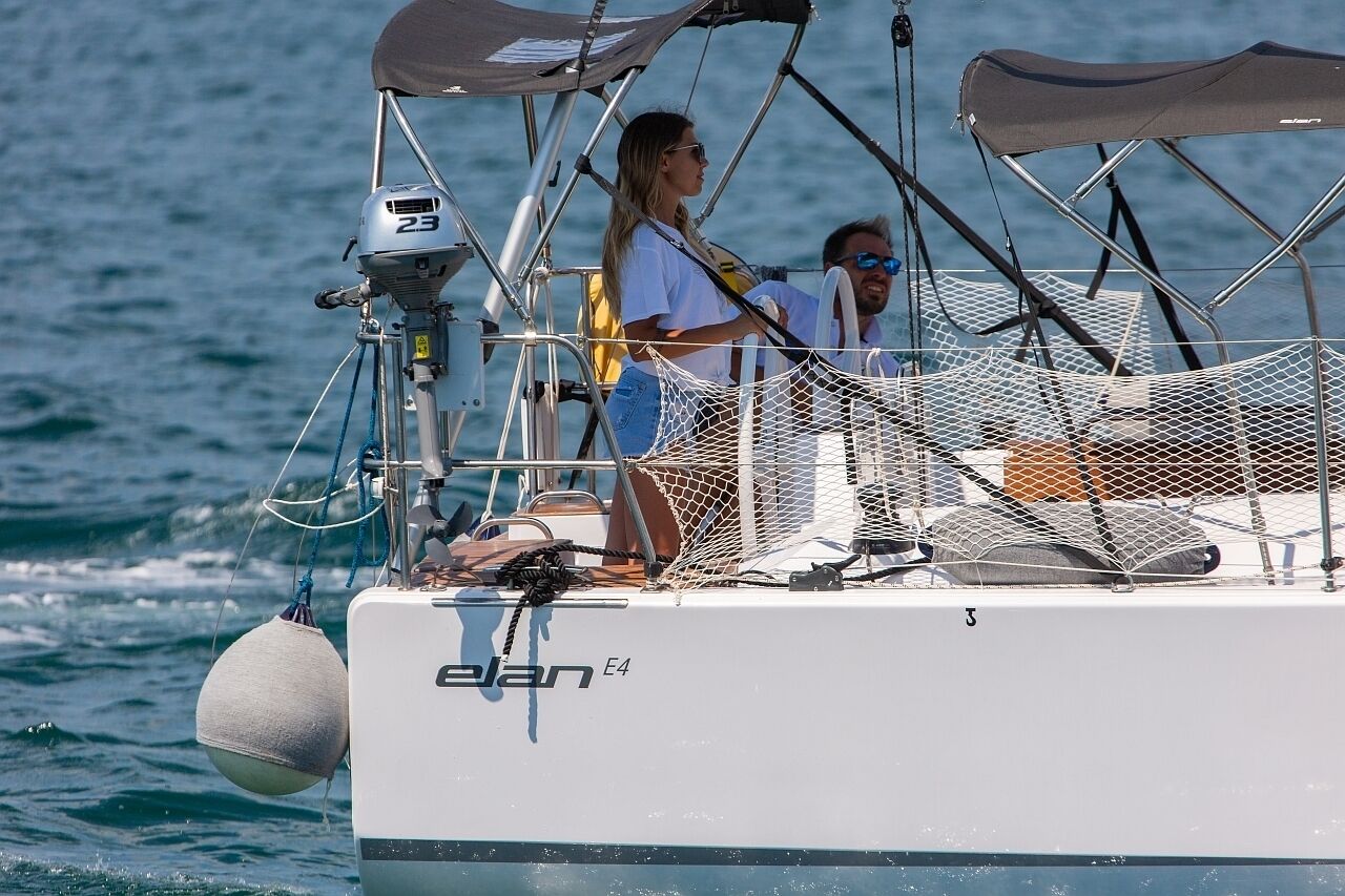 Un velero con camarote, zona con mosquitera y una persona con camisa blanca.