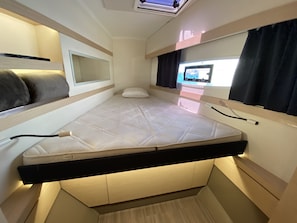 A compact room with a bed, a small window, and a television.