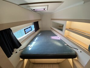 A narrow, enclosed space with a bunk bed, a window with curtains, and a ceiling light fixture. - Sun-Kissed Sailing Adventure in the Majestic Islas Baleares (Ibiza / Eivissa)