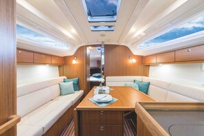 A cozy interior with a central dining table, cushioned seating, and a skylight above. - Sun-Kissed Sailing Adventure in Zadar, Croatia (Zadar)