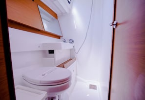 Ein Badezimmer mit Toilette, Waschbecken mit Spiegel und Duschbereich.