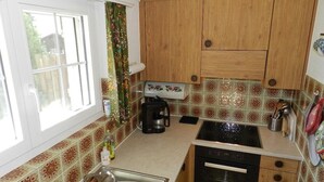 Cocina compacta con alacenas de madera, cafetera y lavavajillas.