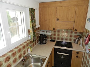 A compact kitchen with wooden cabinets, a coffee maker, and a dishwasher. - Fink Appartement/Fewo, Dusche oder Bad, WC 2-Bettwohnung by Interhome (Zweisimmen)