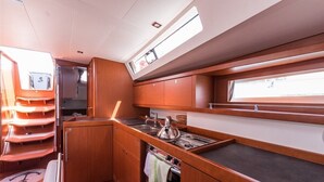 A compact kitchen with wooden cabinets, a stove, and a window. - Sun-Kissed Sailing Adventure in Split, Croatia (Split)