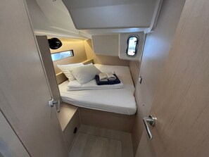 Ein kleiner, kompakter Raum mit einem Bett, einem Fenster und einer Tür.