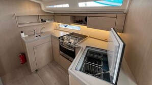 A compact kitchen with a stove, sink, and built-in oven. There are overhead lights and a window. - Sun-Kissed Sailing Adventure in Split, Croatia (Split)