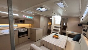 A compact kitchen with a stove, a dining table with a fruit bowl, and a bench. - Sun-Kissed Sailing Adventure in Split, Croatia (Split)