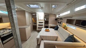 A compact kitchen with a stove, a dining table with a striped tablecloth, and a seating area with a sofa and cushions. - Sun-Kissed Sailing Adventure in Split, Croatia (Split)