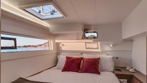 A bedroom with a bed, pillows, a bedside table, a window, and a skylight. - Dubrovnik Delight: A Sun-Kissed Sailing Experience (Komolac)