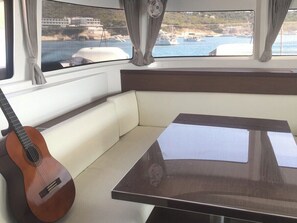 Ein Bootsinnenraum mit gepolsterten Sitzgelegenheiten, einem Tisch und einer Gitarre.