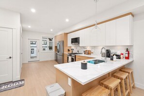 Una cocina moderna con armarios blancos, encimera de mármol y taburetes de madera.
