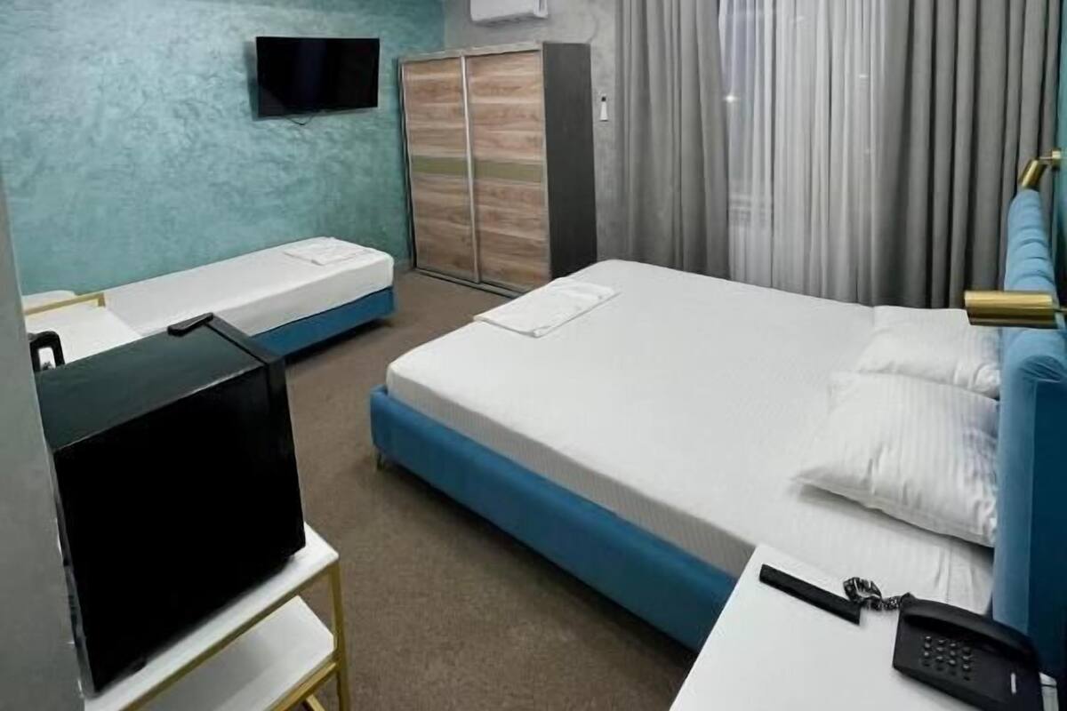 A modern hotel room with a bed, a TV, a desk, and a wardrobe.