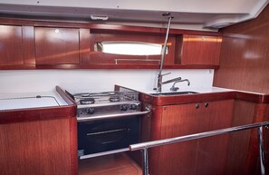 A compact kitchen with wooden cabinets, a stainless steel stove, and a sink. - Sun-Kissed Sailing Adventure in Zadar, Croatia (Biograd na moru)