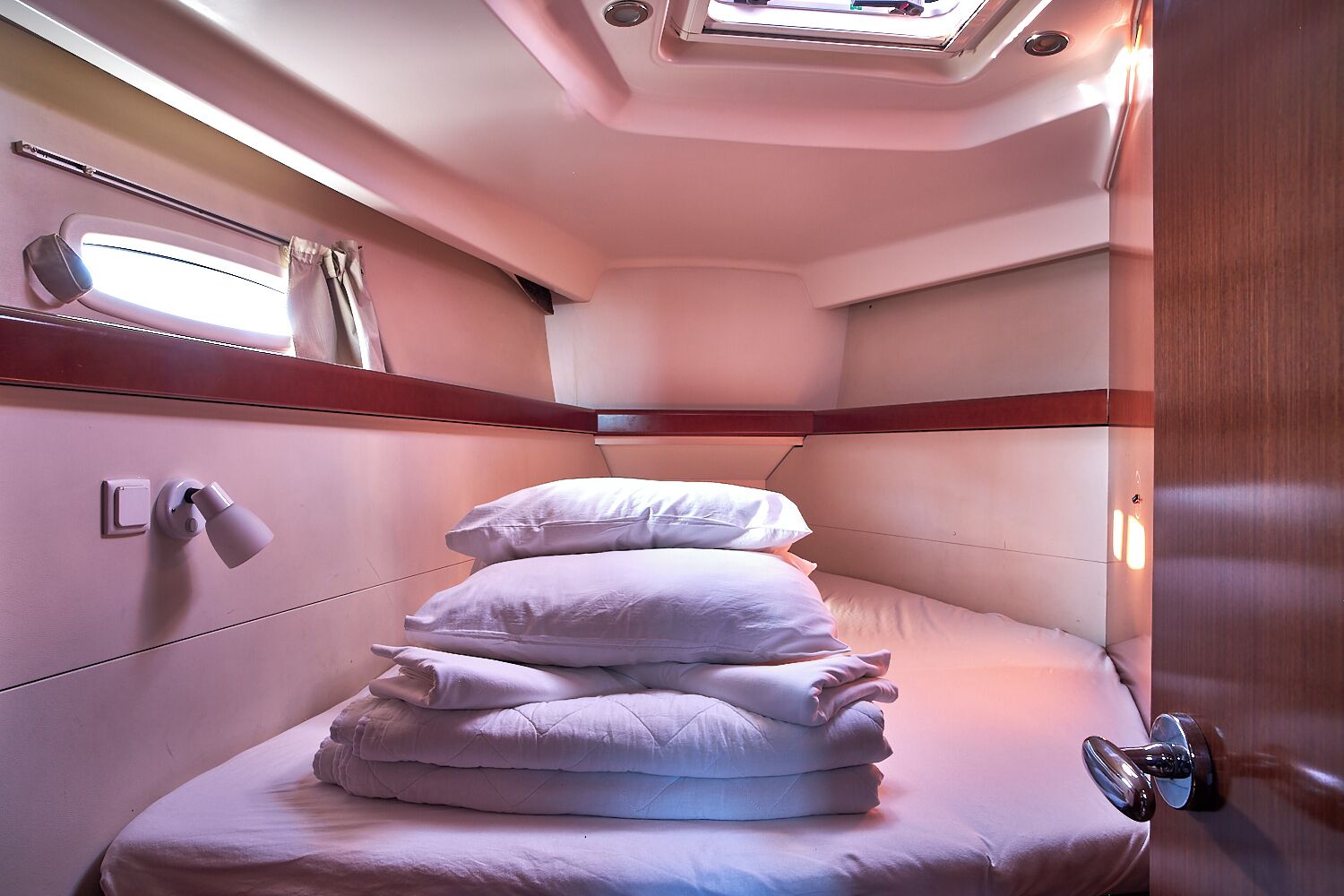 Una cabaña pequeña y bien iluminada con una cama individual, una ventana con cortinas y una mesita de noche.