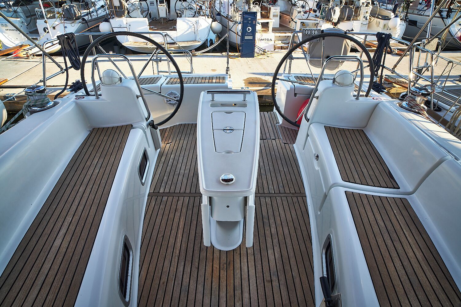 A boat deck with a central seating area, two steering wheels, and a wooden floor.