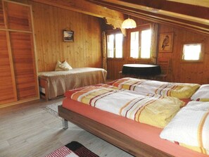 A wooden cabin bedroom with a large bed, a smaller bed, a desk, and a window. - Giferblick Appartement/Fewo, Dusche oder Bad, WC 3-Bettwohnung by Interhome (Zweisimmen)