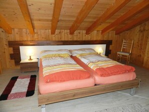 A double bed with a wooden frame in a room with wooden walls and ceiling.