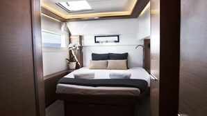 Una camera da letto compatta e ben illuminata con un letto, comodini, una pianta in vaso e una finestra.