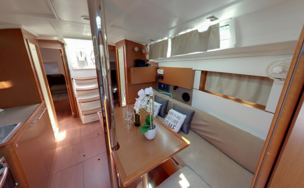 Interior de una caravana compacta con kitchenette, zona de comedor y un pequeño espacio para sentarse.