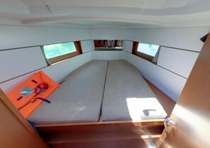 A compact interior with a bed, a small table, and two windows. - Dubrovnik Delight: A Sun-Kissed Sailing Experience (Komolac)