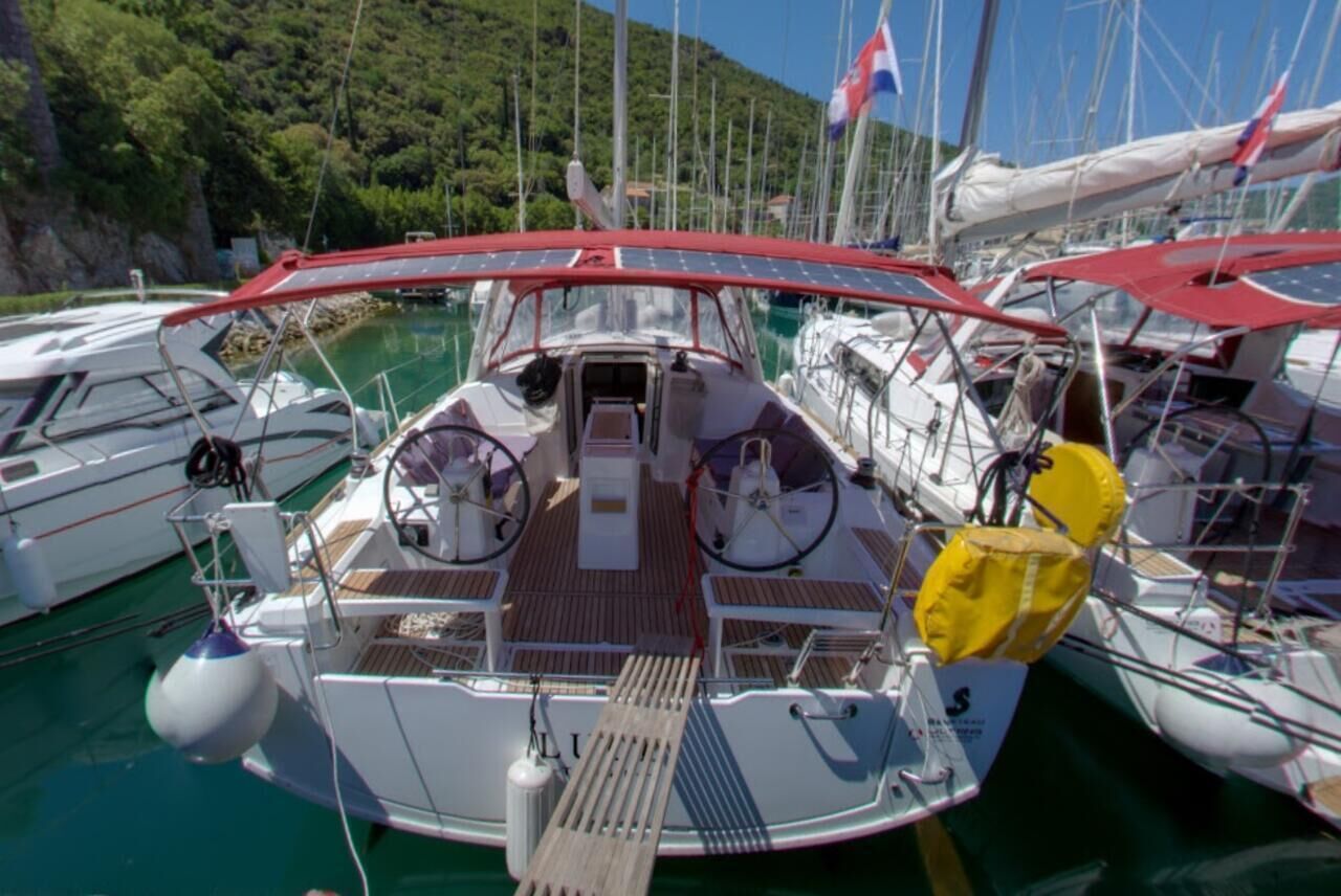 Eine Segelyacht liegt an einem Hafensteg, mit einer überdachten Deck und Steuerpult sowie einer kleinen Kabine.