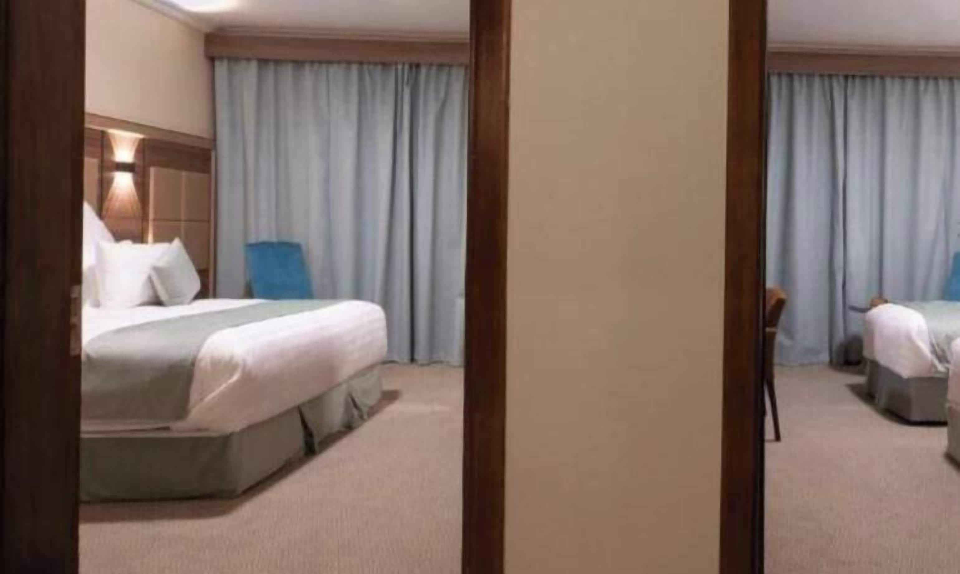 A hotel room with a bed, a chair, and a desk.