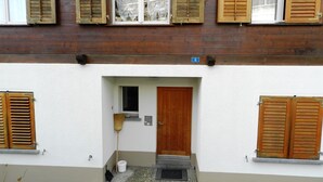 Een gebouw met een houten gevel, een witte buitenmuur en een deur met een nummer erop.