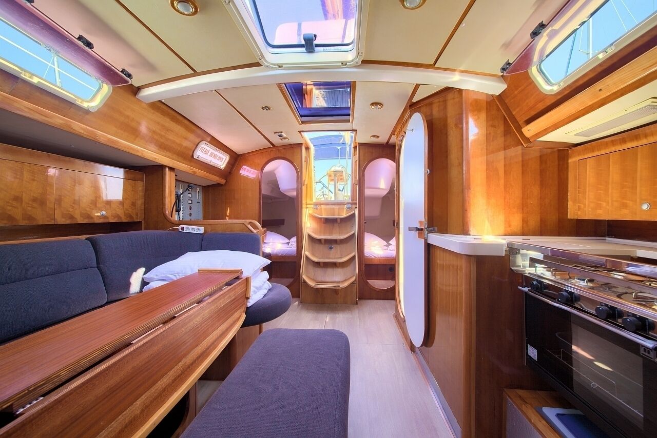 Un intérieur compact comprenant un canapé, une table à manger, un coin cuisine et un petit espace salon avec vue sur le ciel grâce à une lucarne.