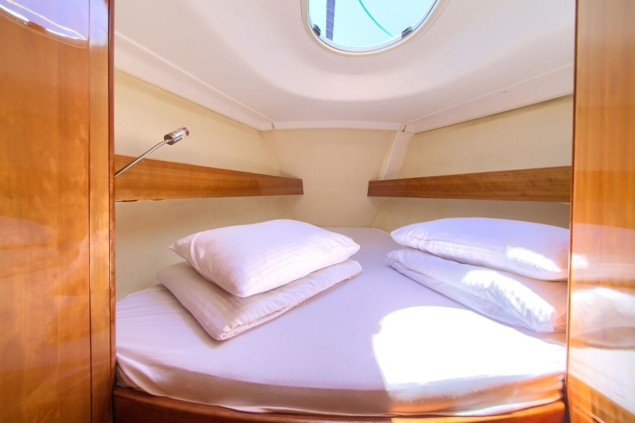 Een kleine kamer met een stapelbed, dakraam en een klein plankje.