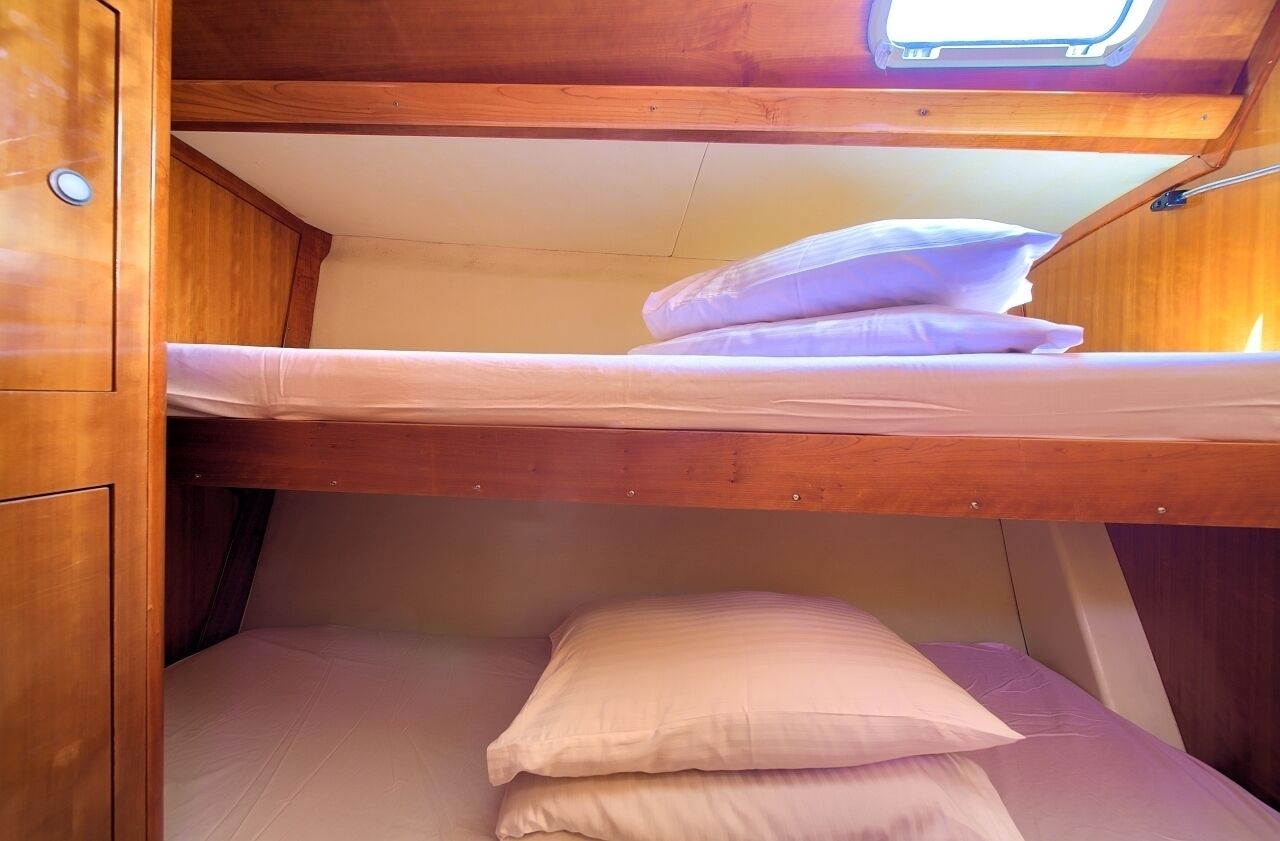 Un lit superposé avec une lucarne au-dessus, des murs en bois et un petit placard.
