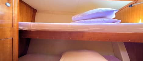 A bunk bed with a skylight above, wooden walls, and a small cabinet.