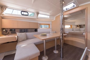 A compact interior with a kitchenette, seating area, and a bed. - Dubrovnik Delight: A Sun-Kissed Sailing Experience (Komolac)