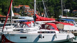 A marina with multiple sailboats docked, featuring a calm water surface and a backdrop of buildings and greenery. - Dubrovnik Delight: A Sun-Kissed Sailing Experience (Komolac)
