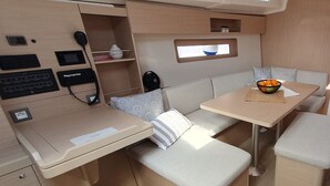 Un intérieur de camping-car compact comprenant un coin cuisine, un espace salon et une petite table sur laquelle se trouve un saladier rempli de fruits.