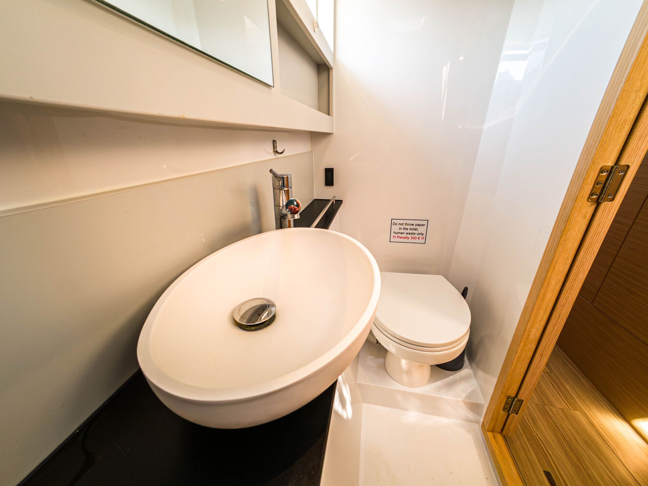 A compact bathroom with a white sink, a toilet, and a wooden door.