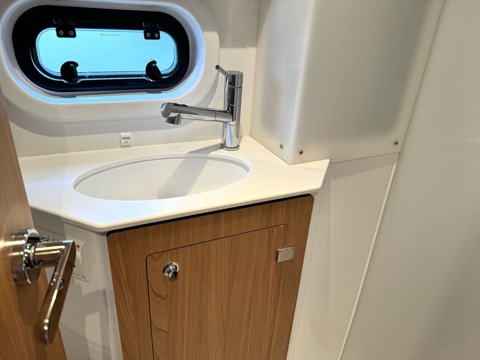 A bathroom with a sink, a window, and a wooden cabinet.