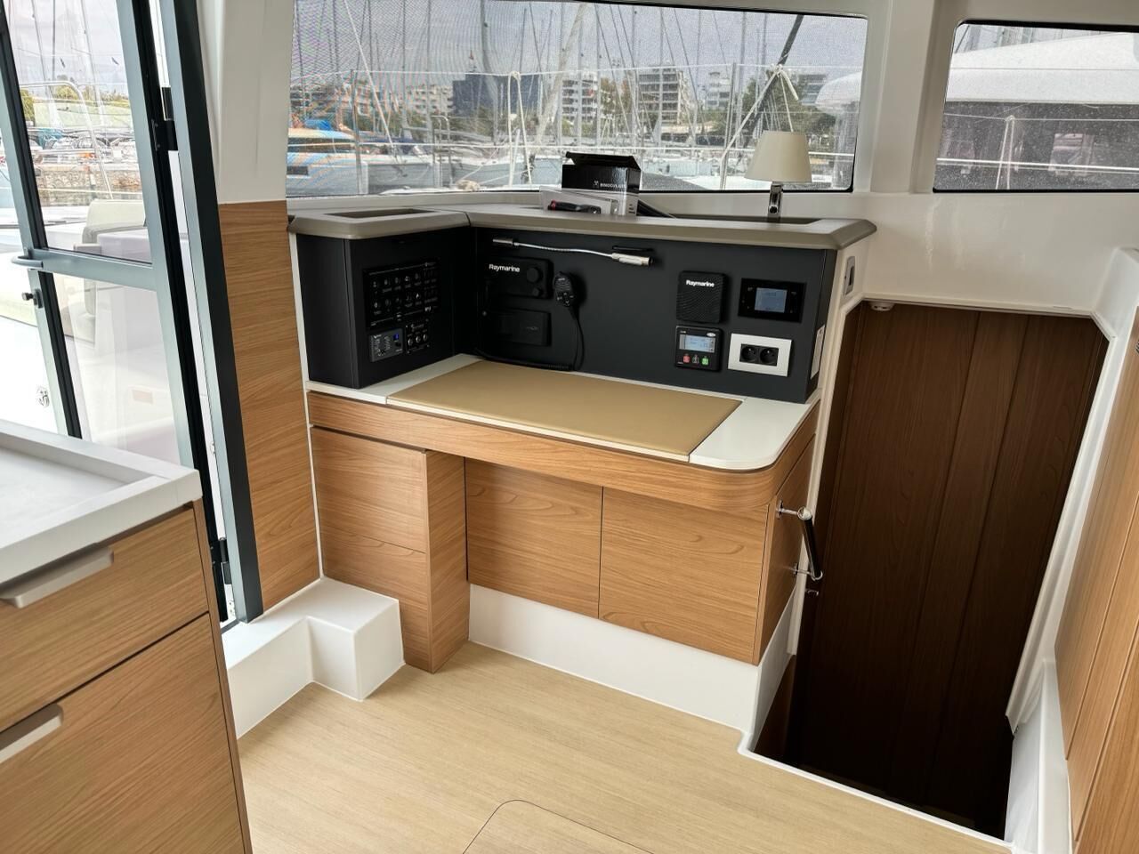 Una cucina compatta con piano di lavoro in legno, elettrodomestici integrati e vista sul porto turistico.