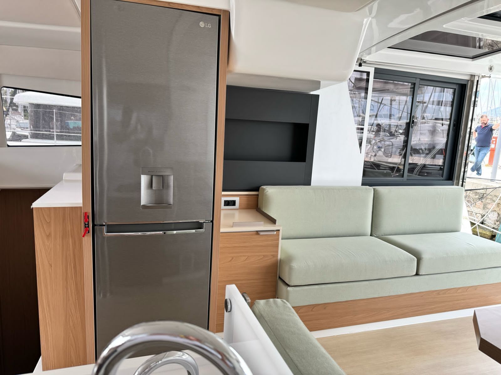 Ein kompakter Wohnbereich mit einem Edelstahlkühlschrank, einer Couch und einem Fenster mit Blick nach draußen.