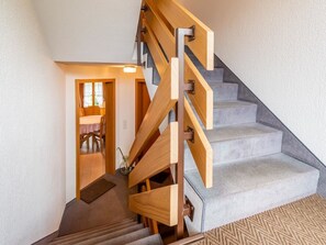 A staircase with wooden handrails and carpeted steps leading to a room with a door and a window. - Résidence Sonnegg (Puric) Appartement/Fewo, Dusche oder Bad, WC, 1 Schlafraum by Interhome (Zweisimmen)
