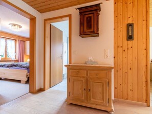 Een houten interieur met een bed, een kast en een deur naar een andere kamer.