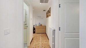 Ein Flur mit Fliesenboden, einem Holzschrank, einem Heizkörper und einer Tür.