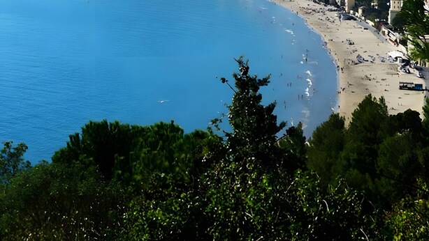 Eine Küstenstadtlandschaft mit Strand, Gebäuden und einem Berg im Hintergrund.