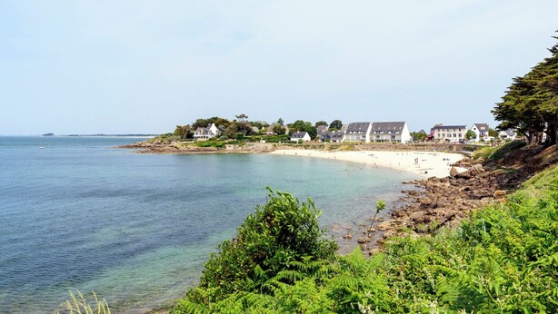 Un hôtel situé sur la côte, composé de plusieurs bâtiments, avec une plage de sable fin et une eau d’un bleu cristallin.