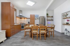 A modern kitchen with wooden cabinets, a dining table, and chairs. - Holiday Home 'Casa Campitanesu' with Mountain View, Private Garden and Wi-Fi (Viddalba)