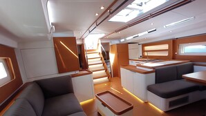 Een modern interieur met een bank, een eethoek en een trap naar een hoger dek.