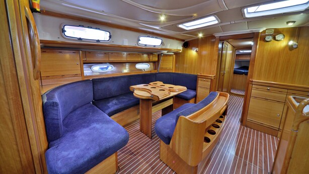 A compact, well-lit interior with a seating area, a table, and a small kitchenette. - Sun-Kissed Sailing Adventure in Islas Sarónicas (Alimos)