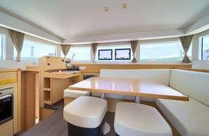 A yacht interior with a dining area, a control station, and a seating area with a view of the sea. - Sun-Kissed Sailing Adventure in Northern Croatia (Punat)