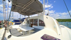 A sailboat with a covered deck area, a table, and a seating arrangement. - Sun-Kissed Sailing Adventure in Northern Croatia (Punat)
